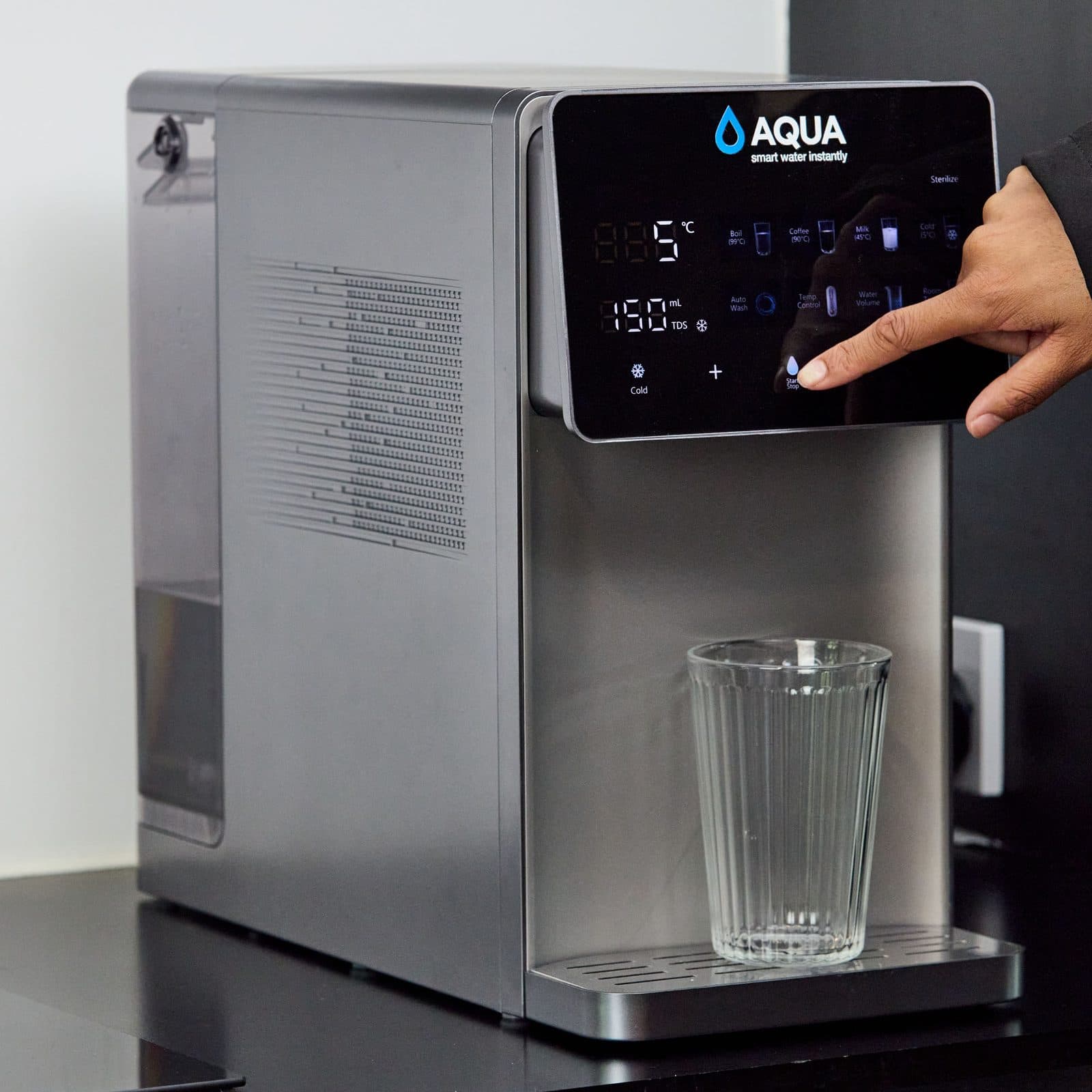 A hand selecting cold water on the Aqua touch display above a glass